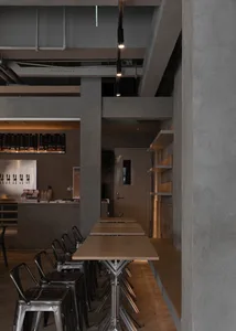 Industrial-themed restaurant interior with metal chairs, concrete pillars, brown wood elements, and white shelving.