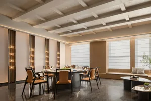 Modern restaurant interior featuring marble floors, black and brown leather dining chairs, and a table with wine glasses and 