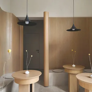 Modern restaurant interior with wooden tables and pendant lights.