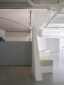 A modern white concrete lobby interior with curved seating and curved white panels.