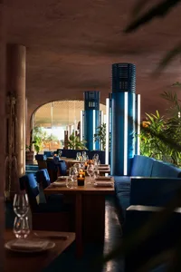 A modern restaurant interior featuring blue textiles and wooden elements.