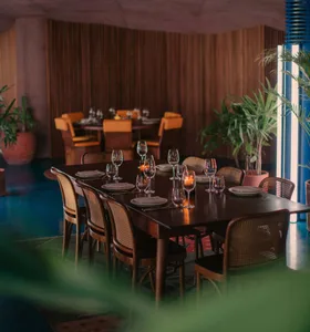 A wooden dining table set for eight people in a modern restaurant dining room.