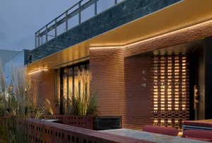Modern restaurant exterior with brick facade and glass doors during a night setting.