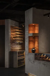 Industrial design restaurant interior with concrete shelves and illuminated brick wall feature.