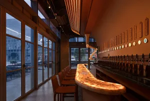 Industrial-style bar interior with a sleek, modern design featuring marble accents and illuminated seating.