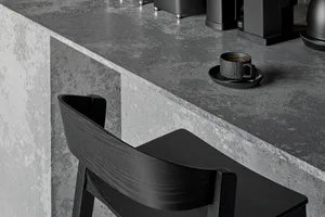 Close-up of a minimalist bar counter with a concrete top, featuring modern seating and coffee cup.