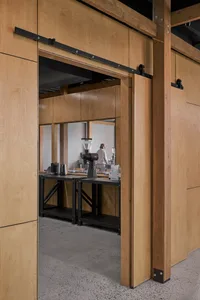 A modern industrial coffee shop interior featuring reclaimed wood walls and metal shelving.