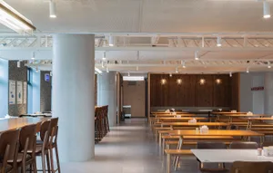 A modern cafeteria interior with wooden furniture and concrete walls.