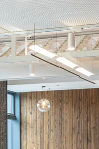 Modern office space with industrial design elements, featuring exposed metal beams, glass panels, and wooden walls.
