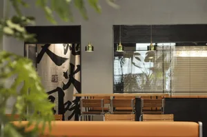 A modern restaurant interior with minimalist decor, wooden tables, pendant lights, and contemporary furniture.