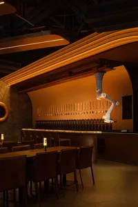 An industrial-themed restaurant bar featuring warm lighting and a sleek, modern design.