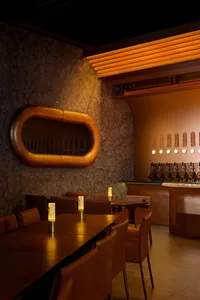 A modern restaurant interior featuring wooden tables, leather chairs, and metallic elements.