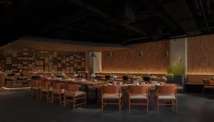 A modern restaurant interior with wooden tables, concrete flooring, and industrial lighting.
