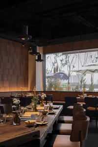 A modern industrial restaurant interior with wood tables, leather seating, and metal accents.