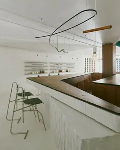 A minimalist industrial cafe interior with concrete countertops and brick walls.