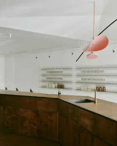 Modern commercial kitchen with minimalist design, featuring a wooden counter and shelving.