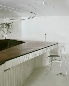 A minimalist modern bar with a concrete countertop and a single metal chair.
