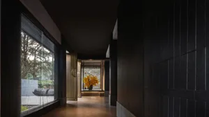 A dark wooden corridor with large windows and a hallway with a vase of yellow flowers.