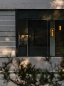 A glass window reflecting a statue and a fireplace with a wood-burning fire.