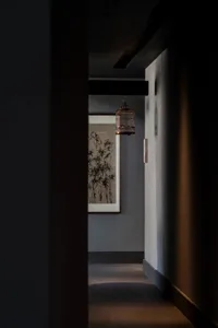 A modern interior hallway with a birdcage hanging from the ceiling, lit by soft, ambient lighting.