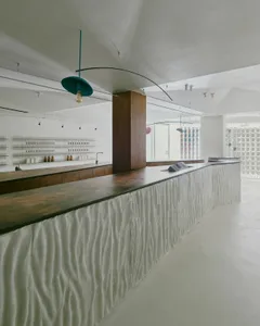 A minimalist restaurant with a white-tiled and concrete counter