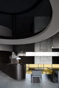A modern restaurant interior featuring dark wood accents and concrete walls.