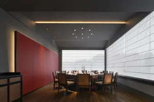 Modern restaurant interior with wooden floor, glass windows, and upholstered chairs