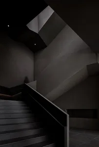 A modern interior space with black metal stairs and railings, featuring a minimalist design and dark walls.
