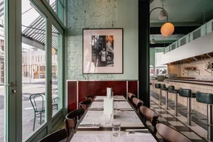 Modern restaurant interior with tables, chairs, and a kitchen counter.