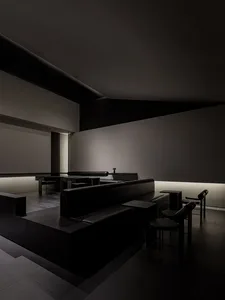 Modern restaurant interior with black leather seating, concrete flooring, and metal accents.