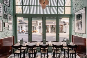 A modern restaurant interior with black chairs, large windows, and metal and glass features.