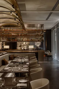 A photograph showcasing a modern luxury restaurant dining interior with metallic elements and leather.