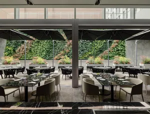 Modern minimalist restaurant interior with marble tables, black stone and chairs, and a living wall.