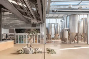 Industrial-style indoor brewery with polished concrete flooring, stainless steel brewing tanks, and a minimalist interior des