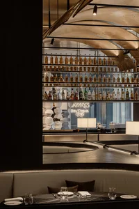Industrial design restaurant interior with metal shelves, glass bottles, and marble tables.