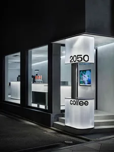 A minimalist coffee shop exterior with a metal exterior, featuring a white sign with black text displaying 'coffee' and '2050