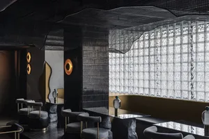 Modern interior design featuring a cafe-bar area with glass brick walls, concrete surfaces, and contemporary lighting fixture