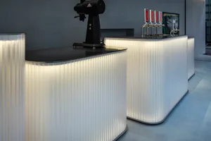 A modern coffee shop counter with illuminated metal panels.