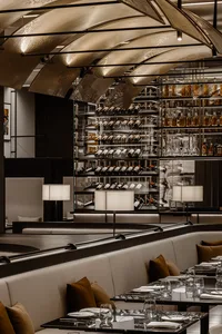 Modern restaurant interior with glass shelves, steel accents, and leather seating