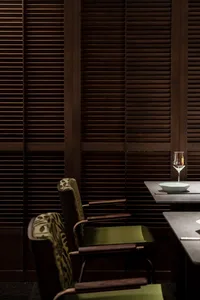 A minimalist restaurant interior featuring wooden decor and green furniture.