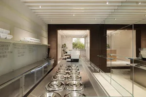 Modern industrial coffee shop with metallic countertops and glass walls.
