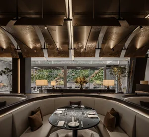 Modern restaurant interior with elegant marble table setting, leather seating, and contemporary lighting fixtures.