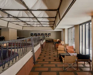 A modern lounge area featuring plush, natural-fiber armchairs and a high, textured floor, illuminated by ambient lighting.