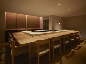 Modern minimalist restaurant interior with wooden furniture and concrete countertops.