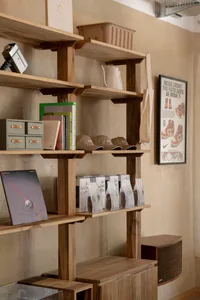 Minimalist interior design featuring wooden shelves with books, bags, and other products displayed.