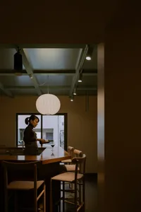 Minimalist kitchen bar area with wood furniture and pendant lights.