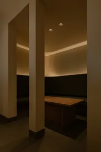 A modern booth area in a restaurant or cafe with wooden tables and cushions on a concrete floor.
