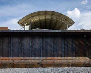 Industrial building exterior with a steel roof and concrete base.