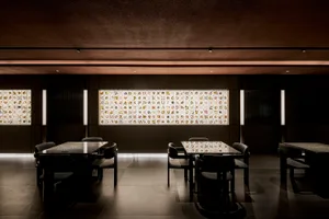 A modern restaurant interior with black materials and illuminated wall art.