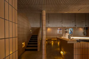 Interior view of a modern coffee shop with tile walls and concrete elements